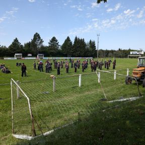 Dutzende Shinson-Hapkido-Schwarzgürtel halten Langstöcker in ihrer rechten Hand, stehen in einem abgegrenzten Bereich auf einem Fußballfeld.