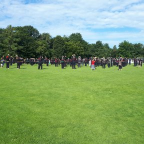 Große Gruppe Hapkidos beim Aufwärmtraining auf einem Sportplatz. Im Hintergrund ein Shinson-Hapkido-Banner.